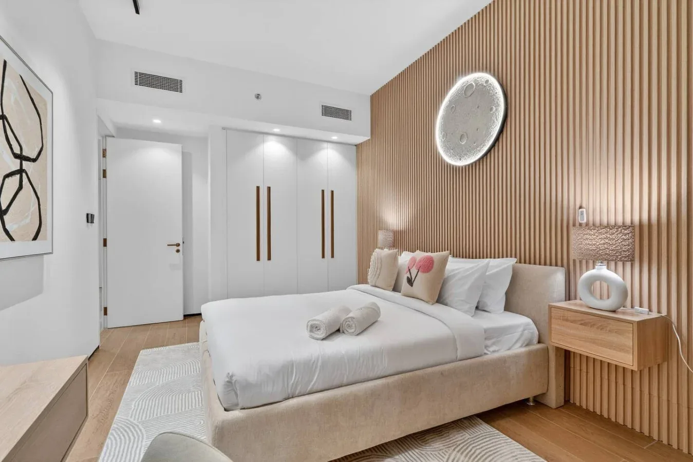 Un dormitorio luminoso con una cama frente a una pared de listones de madera.