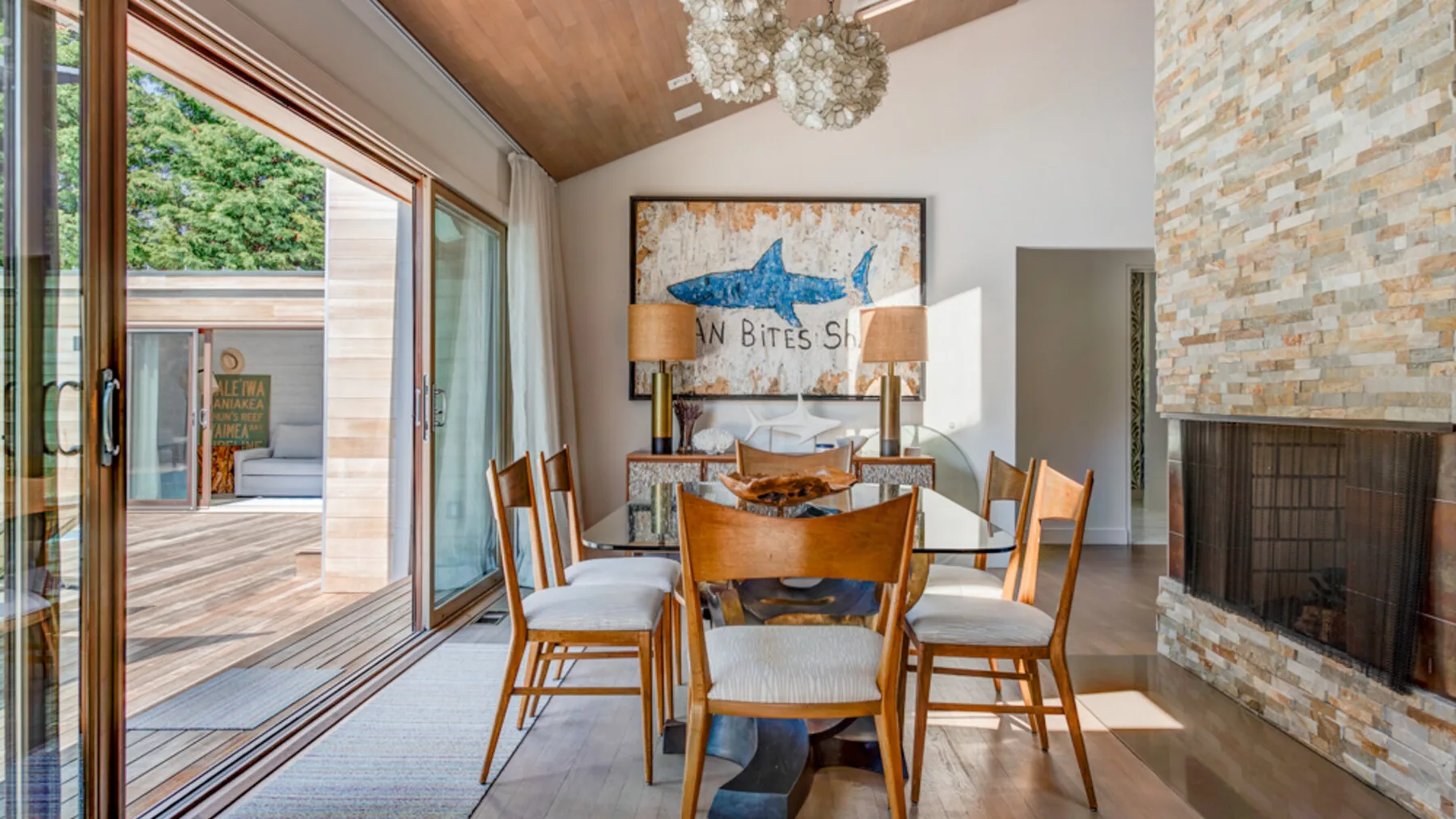 A dining area with a wooden table and chairs beside large sliding glass doors.