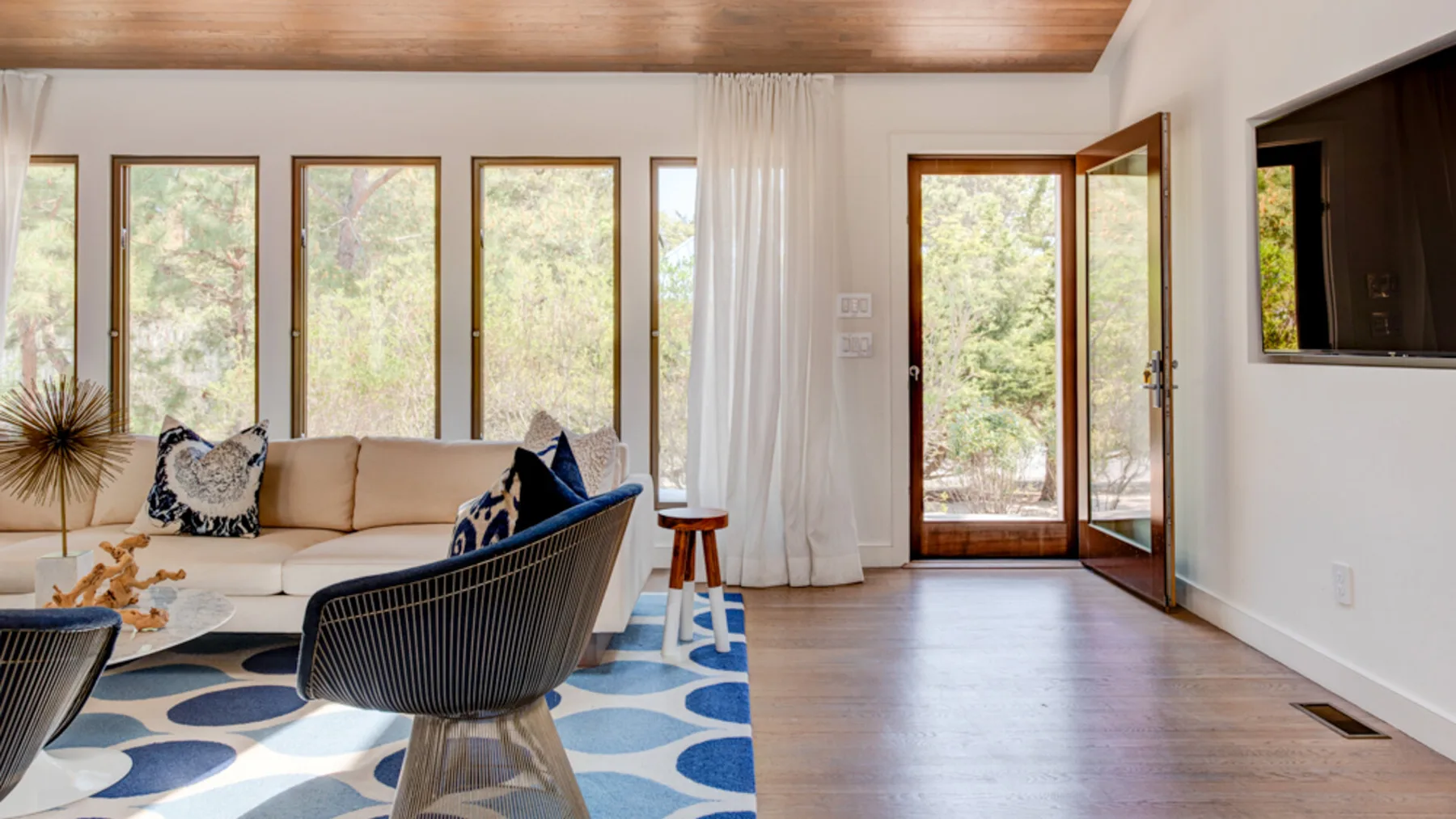 A bright living room with seating, tall windows, and an open glass door.