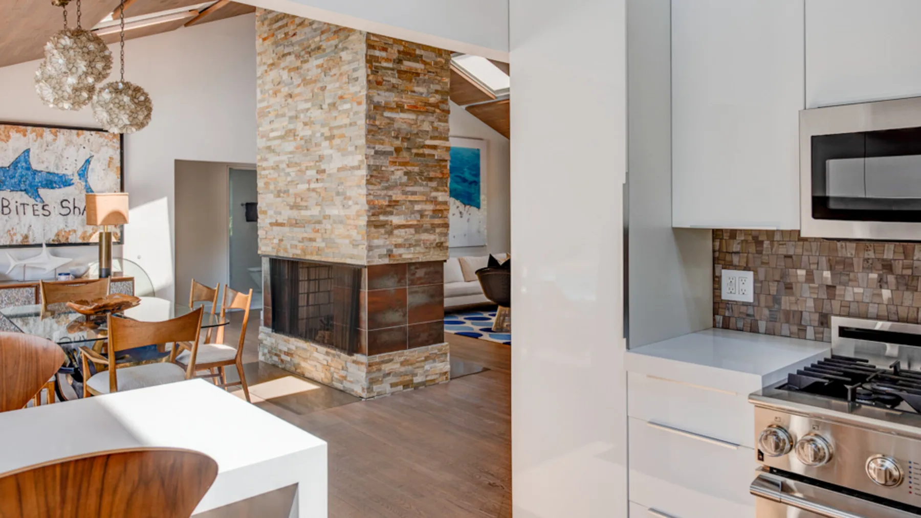 An open-plan kitchen and dining area with a stone-clad fireplace between them.