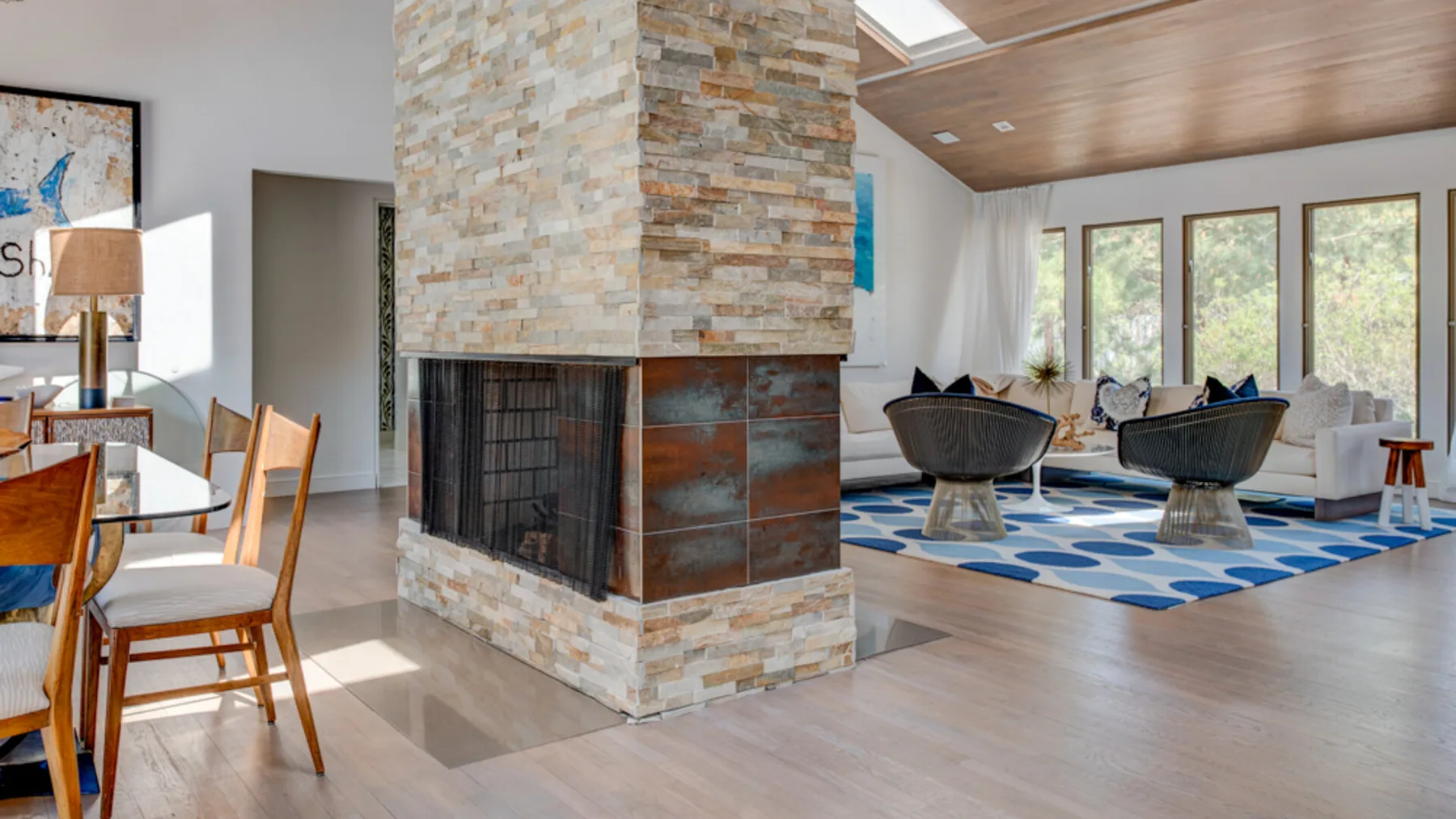 An open living and dining area with a stone fireplace and seating.
