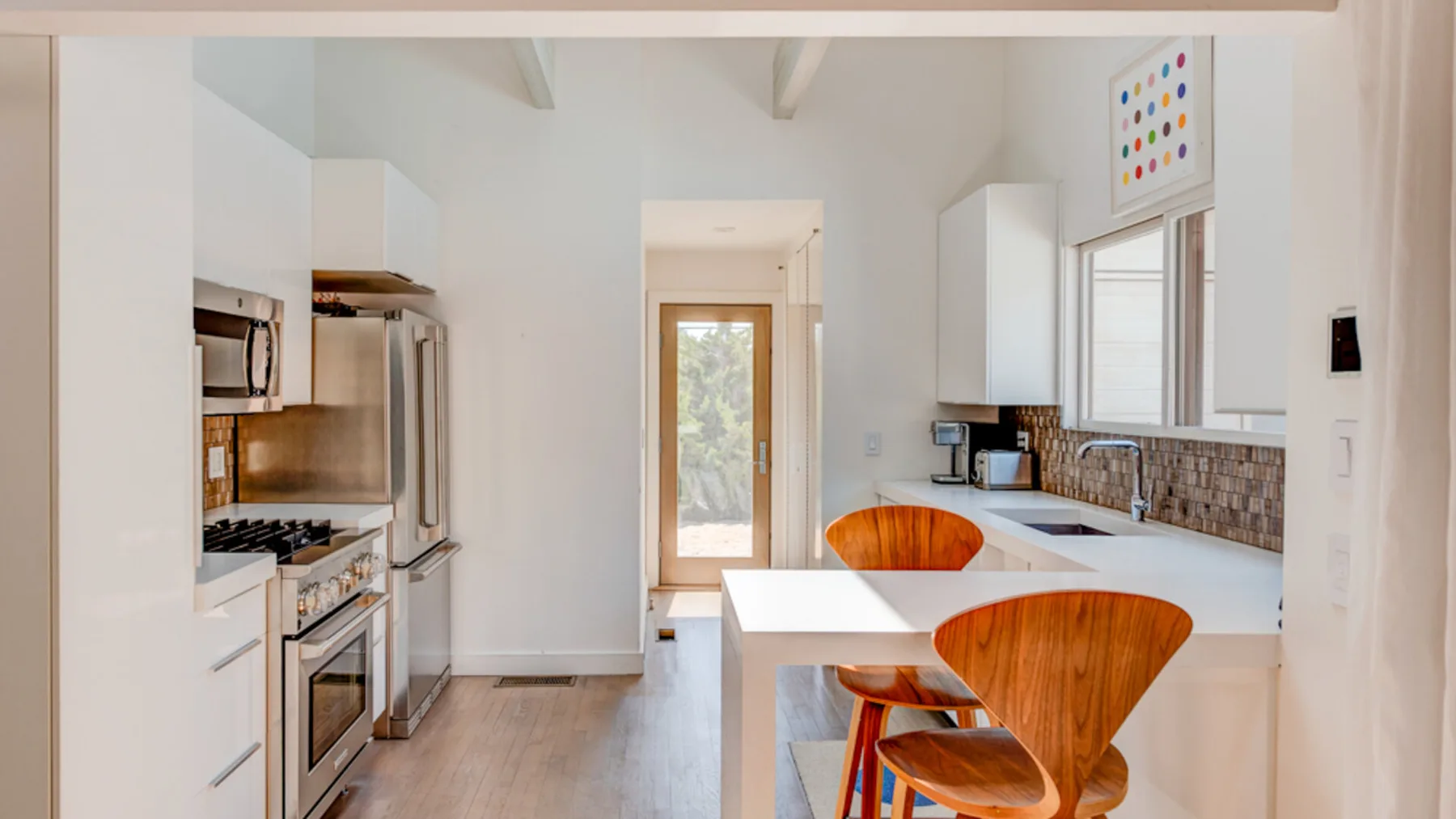 A bright kitchen with a white island and wooden seating.