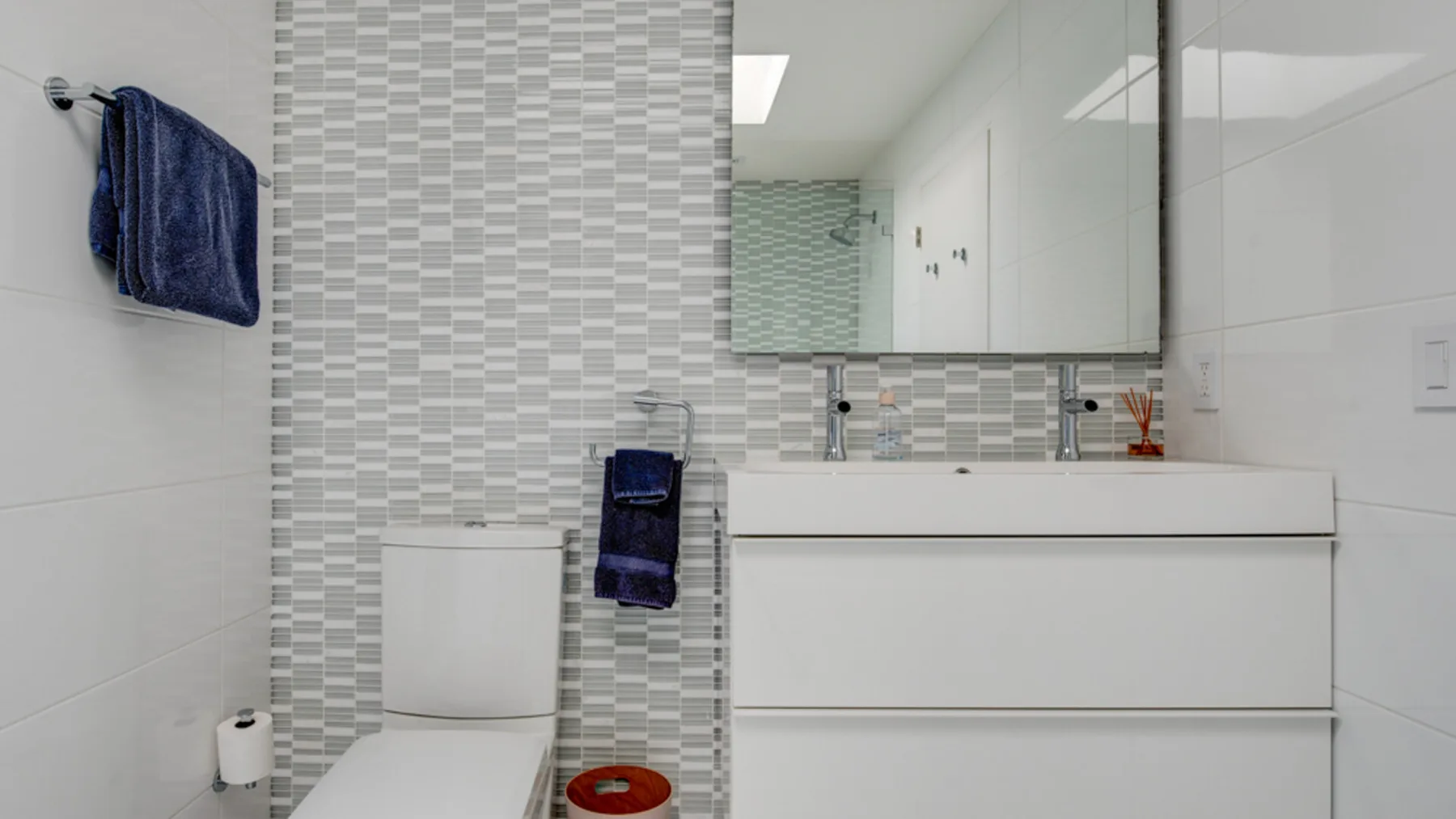 A bathroom vanity with a sink and mirror beside a toilet.