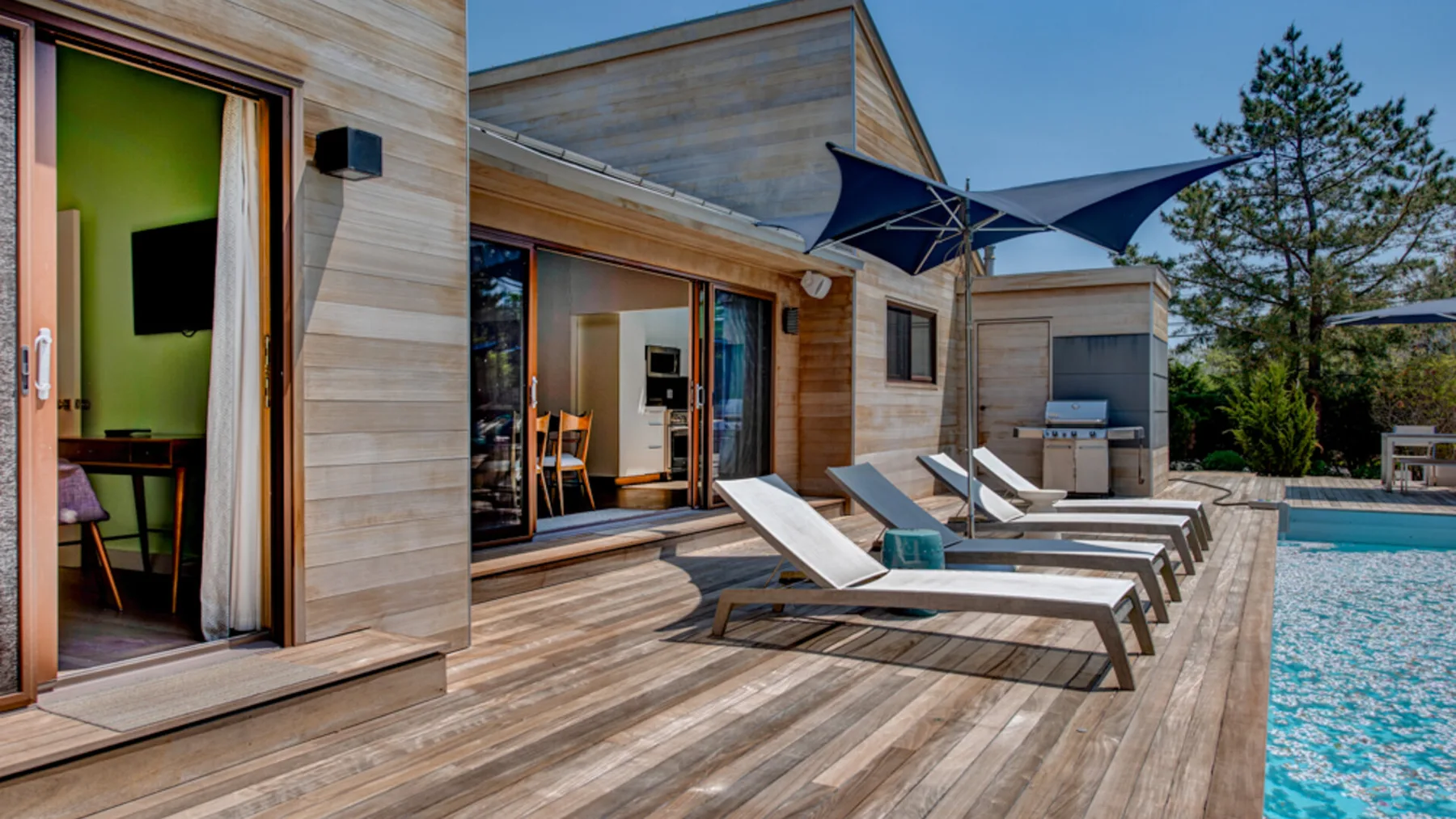 A wooden pool deck with lounge seating beside a swimming pool.