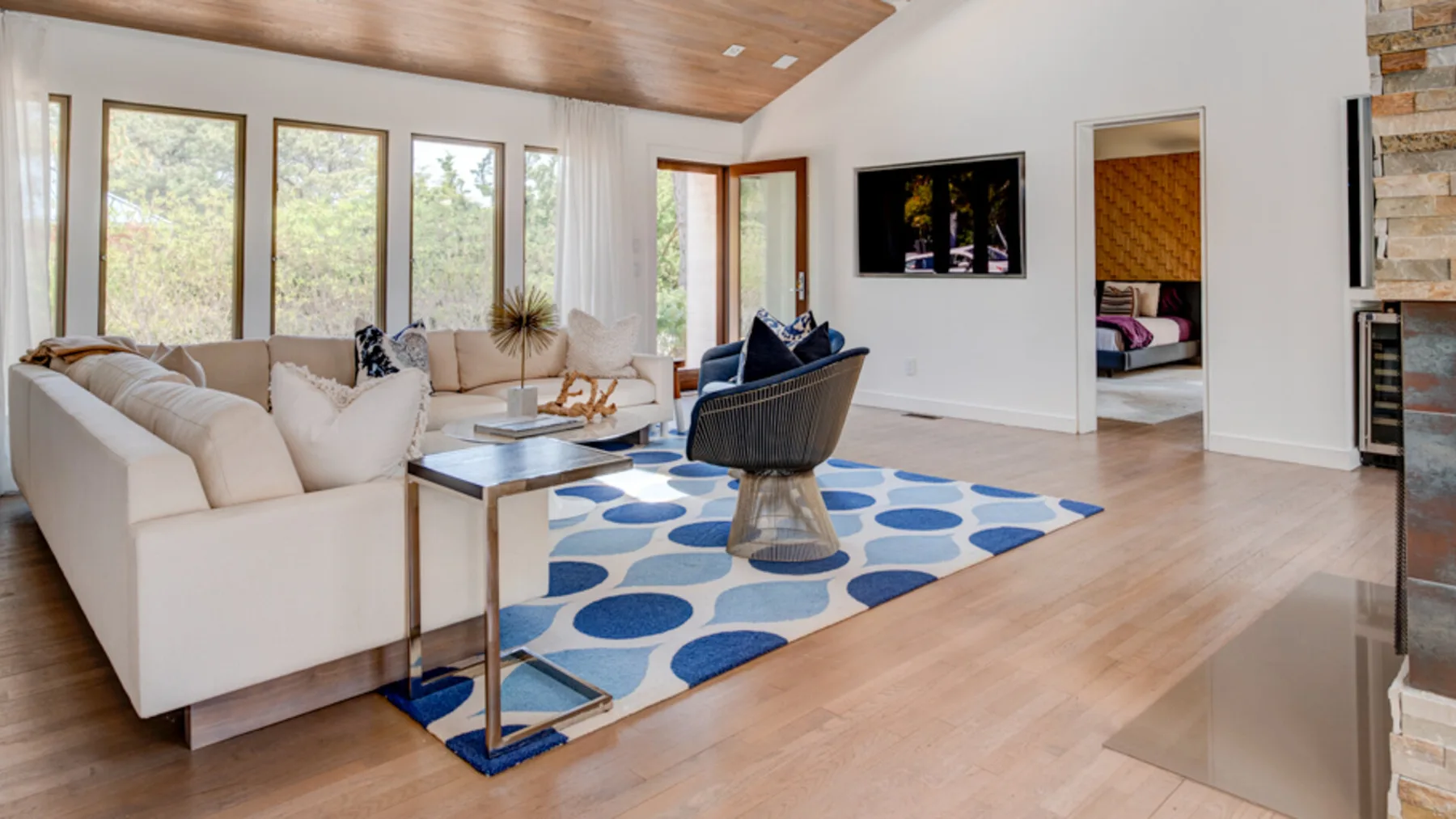 A bright living room with seating around a low table and a patterned rug.