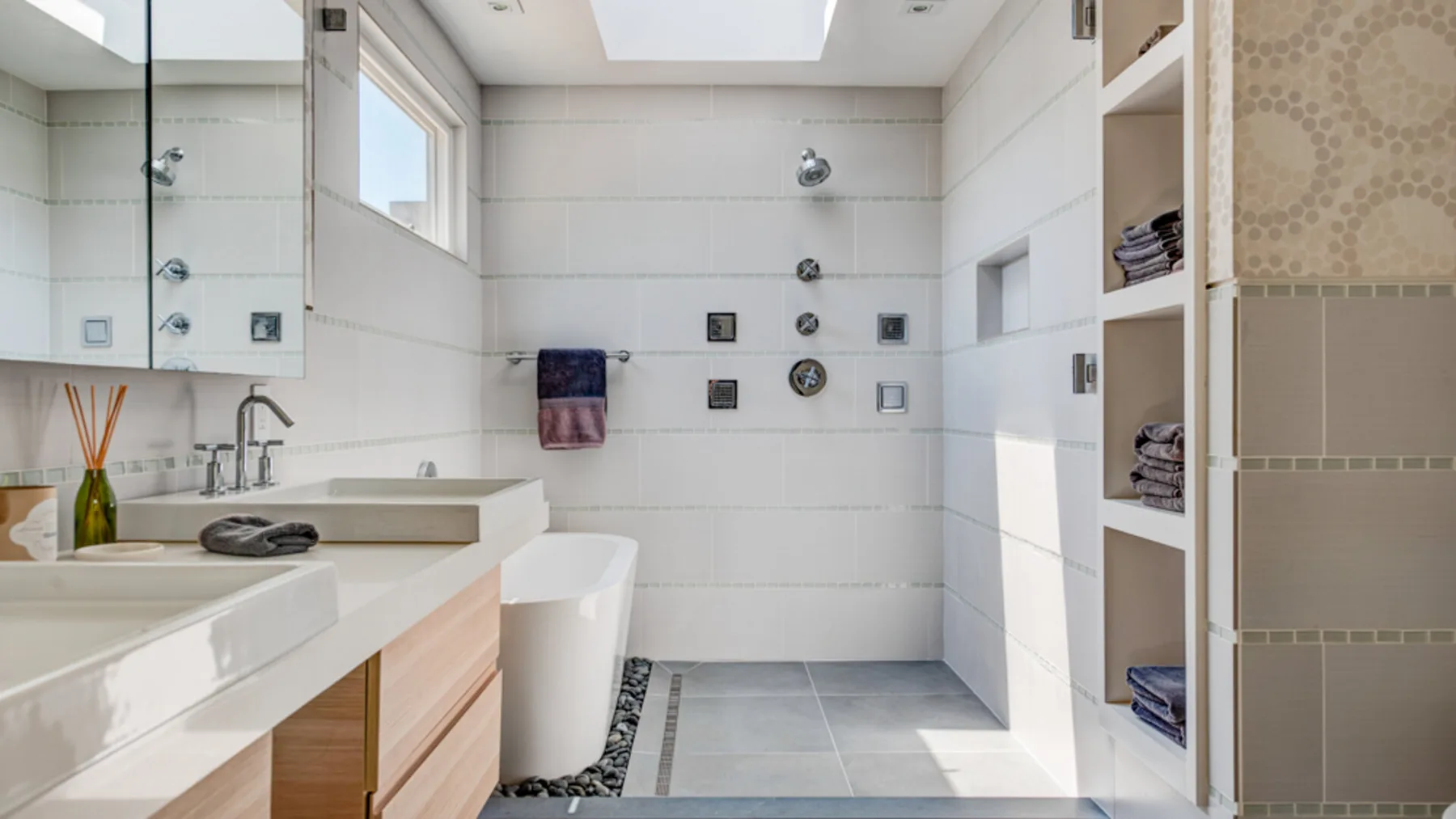 A bright tiled bathroom with a bathtub, glass shower, and vanity.