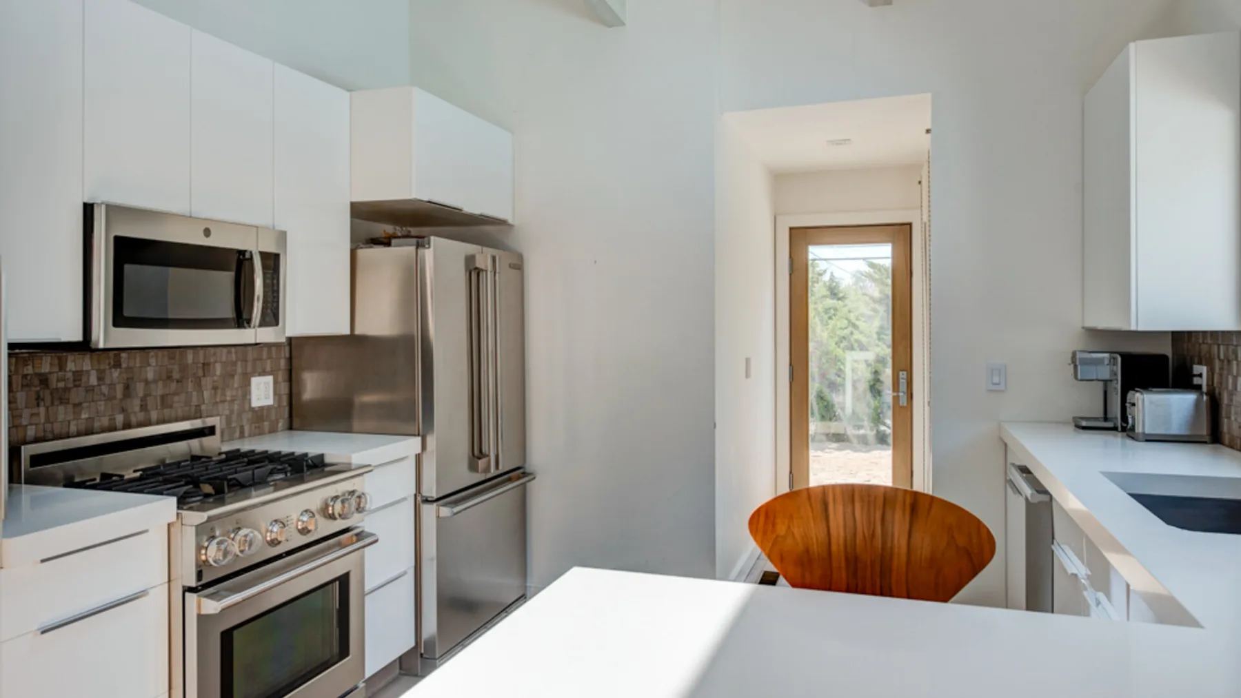 A bright kitchen with white cabinetry and a wooden dining table.