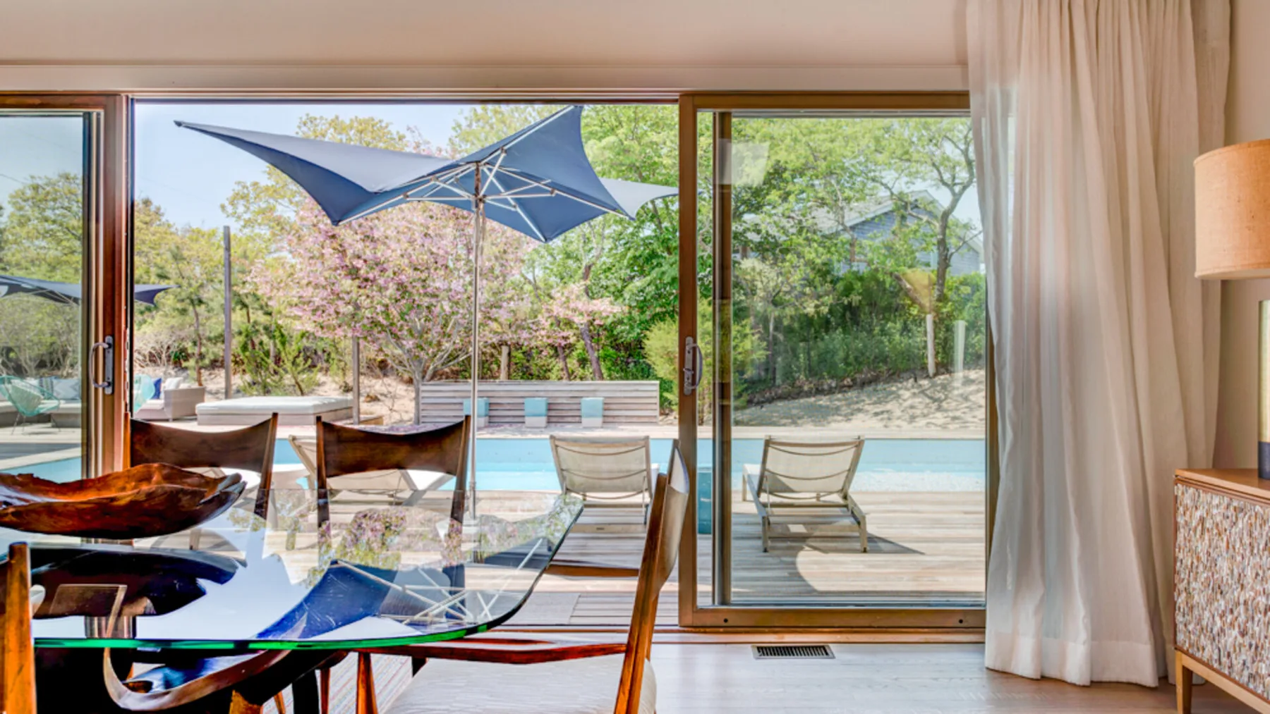 A dining area opens onto an outdoor patio with seating and a shade canopy.