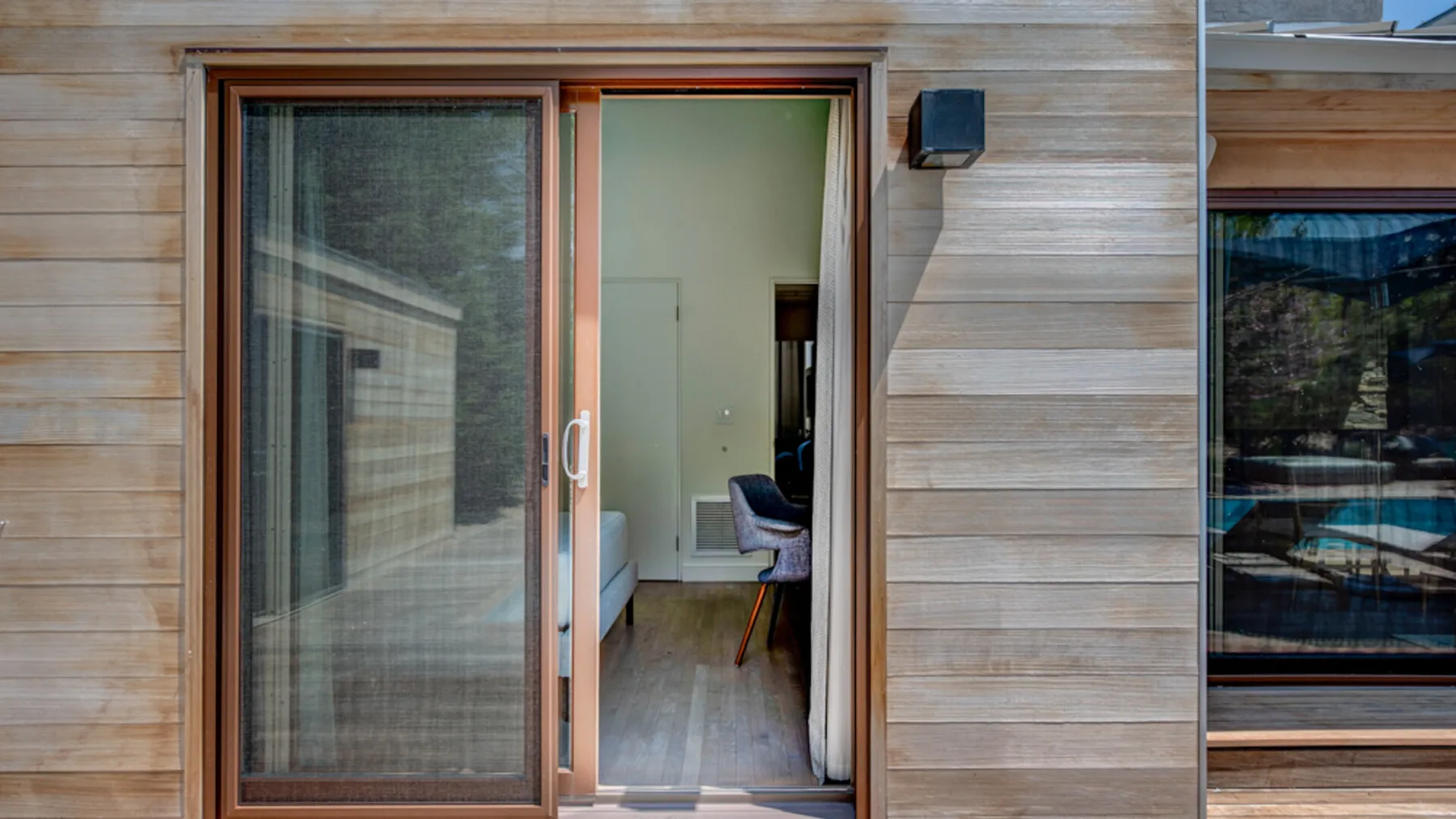 A sliding glass doorway opens onto a room with seating.