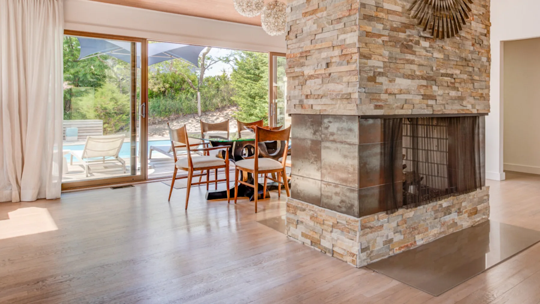 A bright living and dining area with a stone fireplace and patio doors.