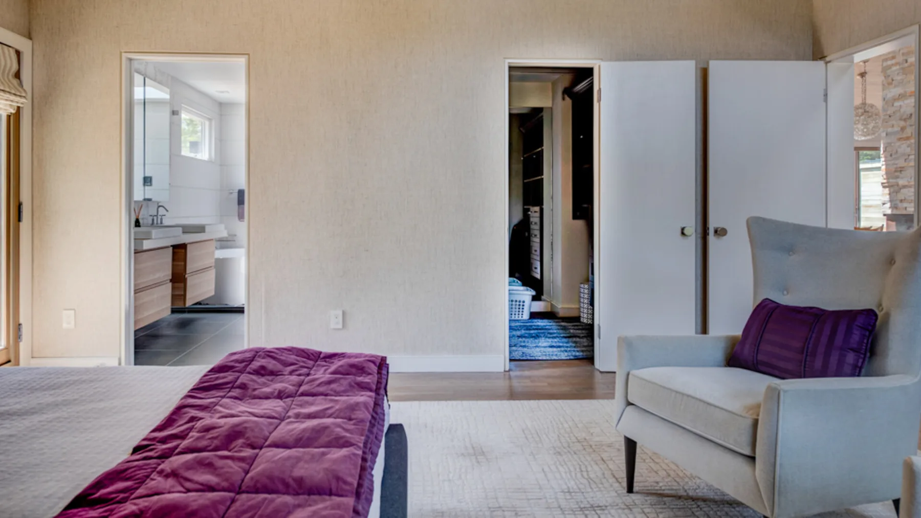 A bedroom with a bed in the foreground and a seating area beside the doorway.
