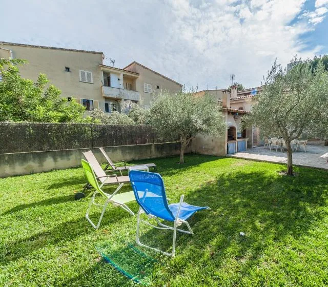 Un patio con césped, asientos al aire libre, árboles y un muro bajo de piedra.