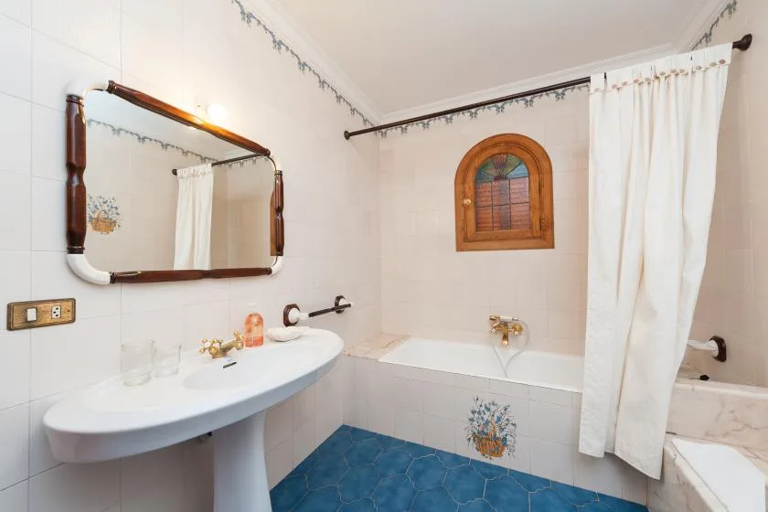 A tiled bathroom with a sink, mirror, and white shower curtain.