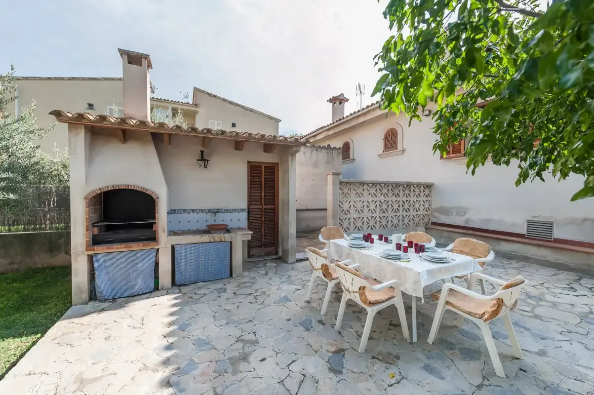A paved outdoor patio has a dining table beside a built-in barbecue.