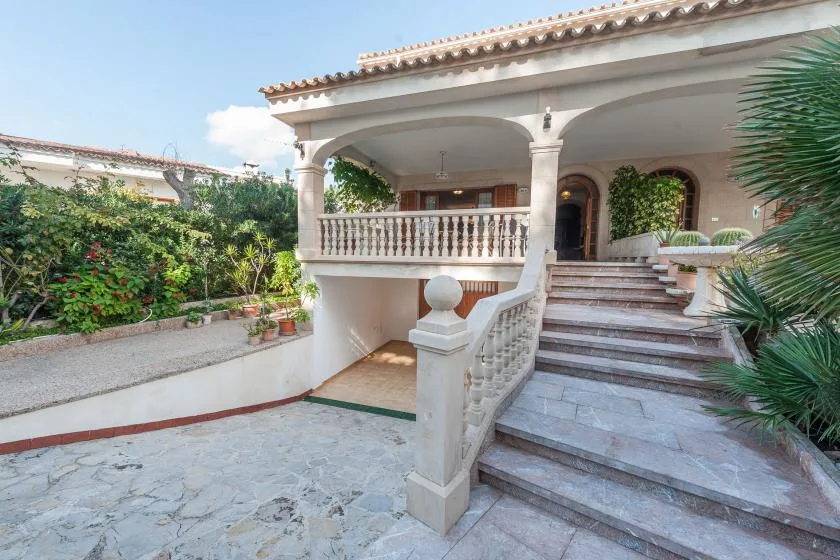 A stone staircase leads to a covered porch beside a landscaped courtyard.