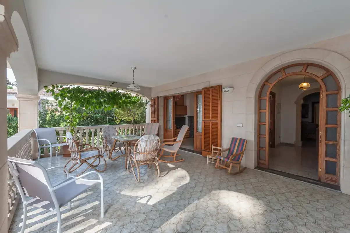 A covered patio with outdoor seating and open doors leading indoors.
