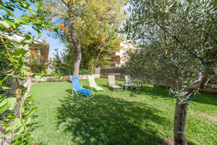 Un jardín de césped con asientos al aire libre bajo árboles frondosos.