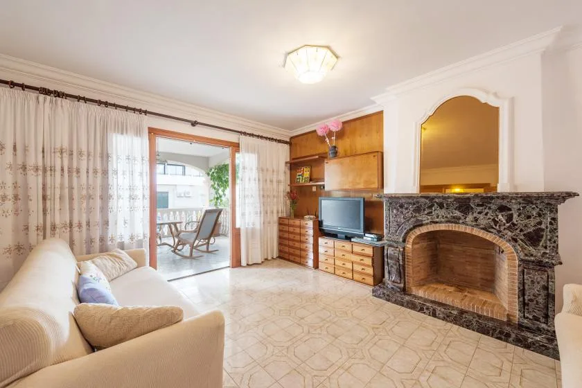 A bright living room with seating, a television, and a fireplace.