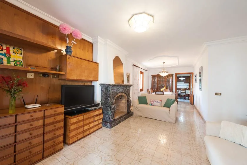 A living room with a television cabinet, stone fireplace, and seating.