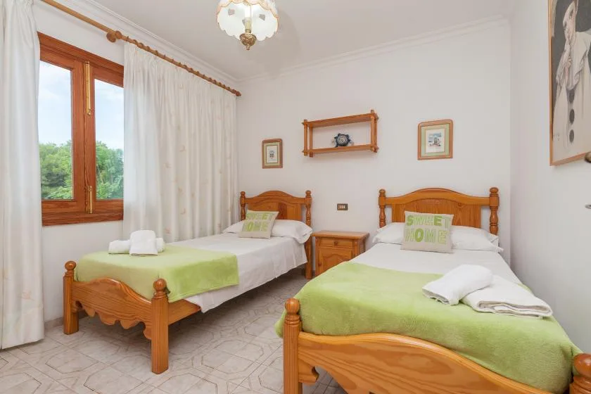 A bedroom with two wooden beds dressed in white and green linens.