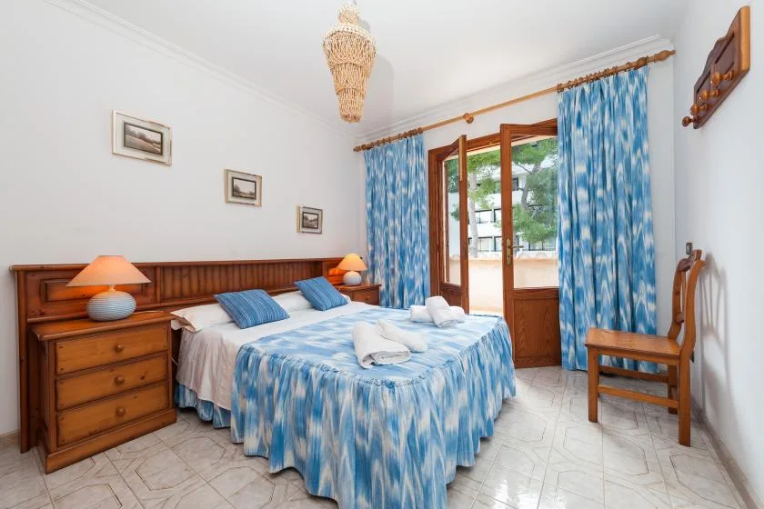 A bedroom with a double bed dressed in blue patterned bedding and blue curtains.