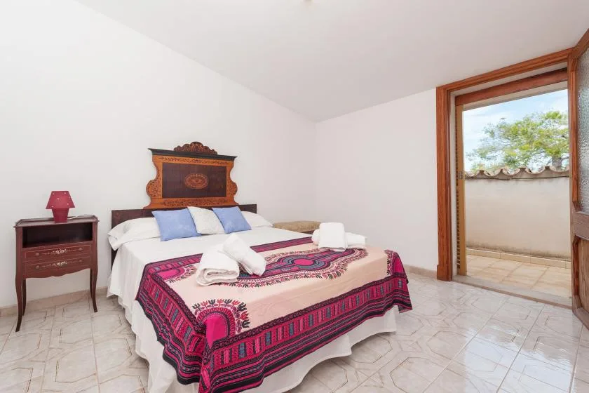 A bedroom with a bed covered by a colorful patterned blanket.
