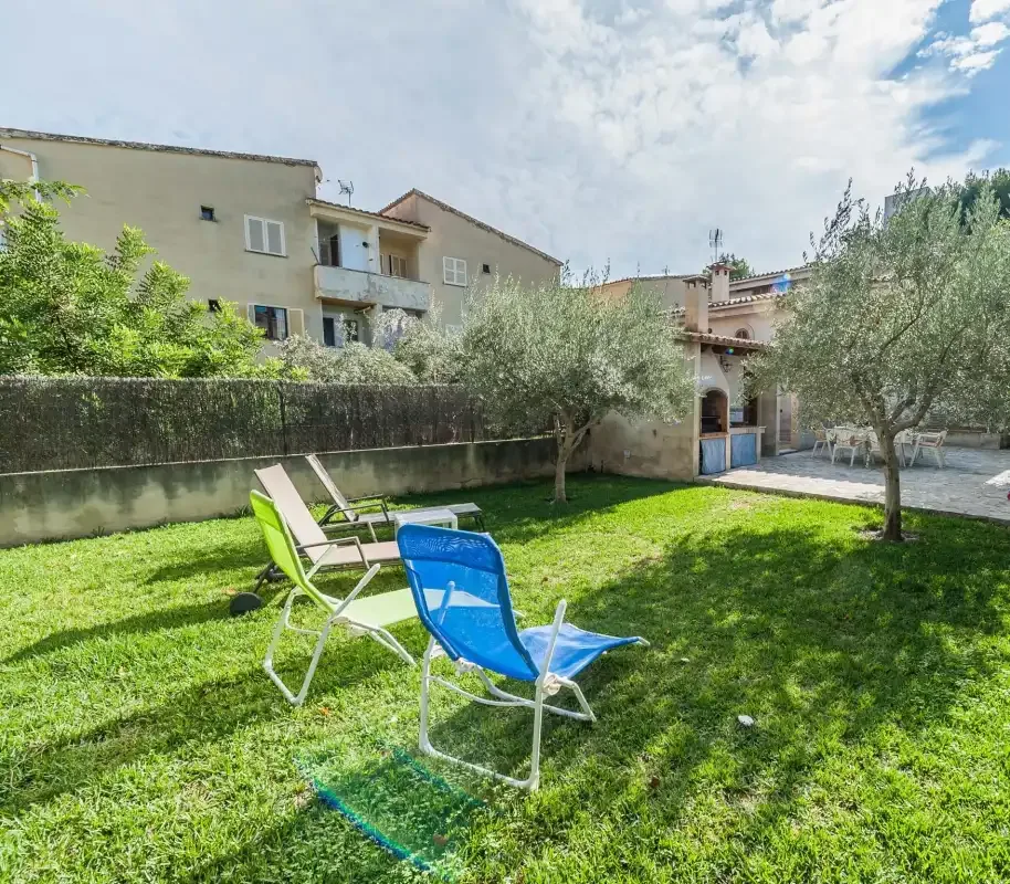 A grassy outdoor seating area with trees and residential buildings in the background.