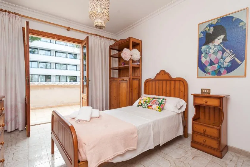 A bedroom with a wooden bed, bedside table, and an open balcony doorway.
