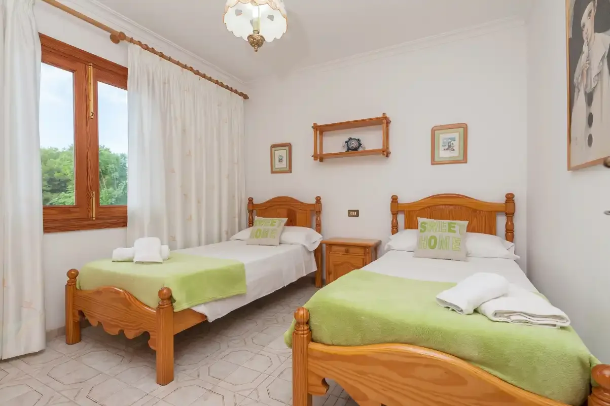 A bedroom with two wooden beds dressed in pale green bedding.