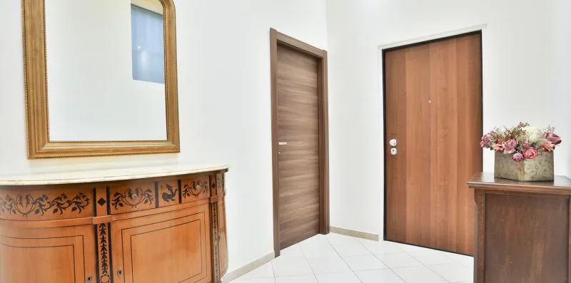 An entryway with wooden doors, a decorative cabinet, and flowers.