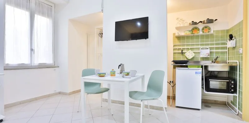 A bright dining area with a table, chairs, and a wall-mounted television.