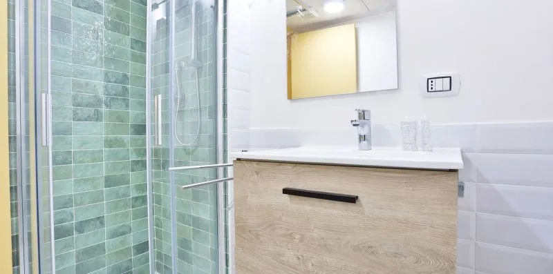 A bathroom vanity with a mirror beside a glass shower.