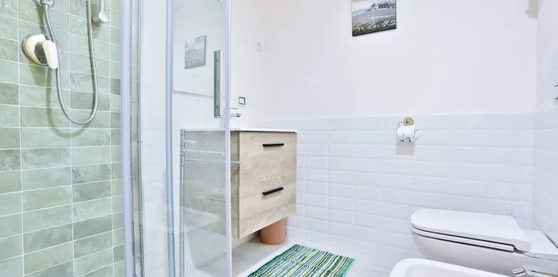A bathroom with a glass shower, vanity, and toilet.