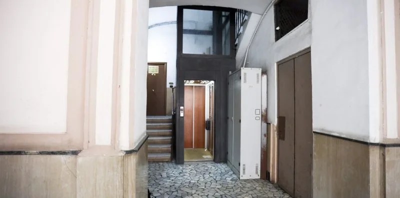An interior entry hall with a small elevator and patterned tile floor.
