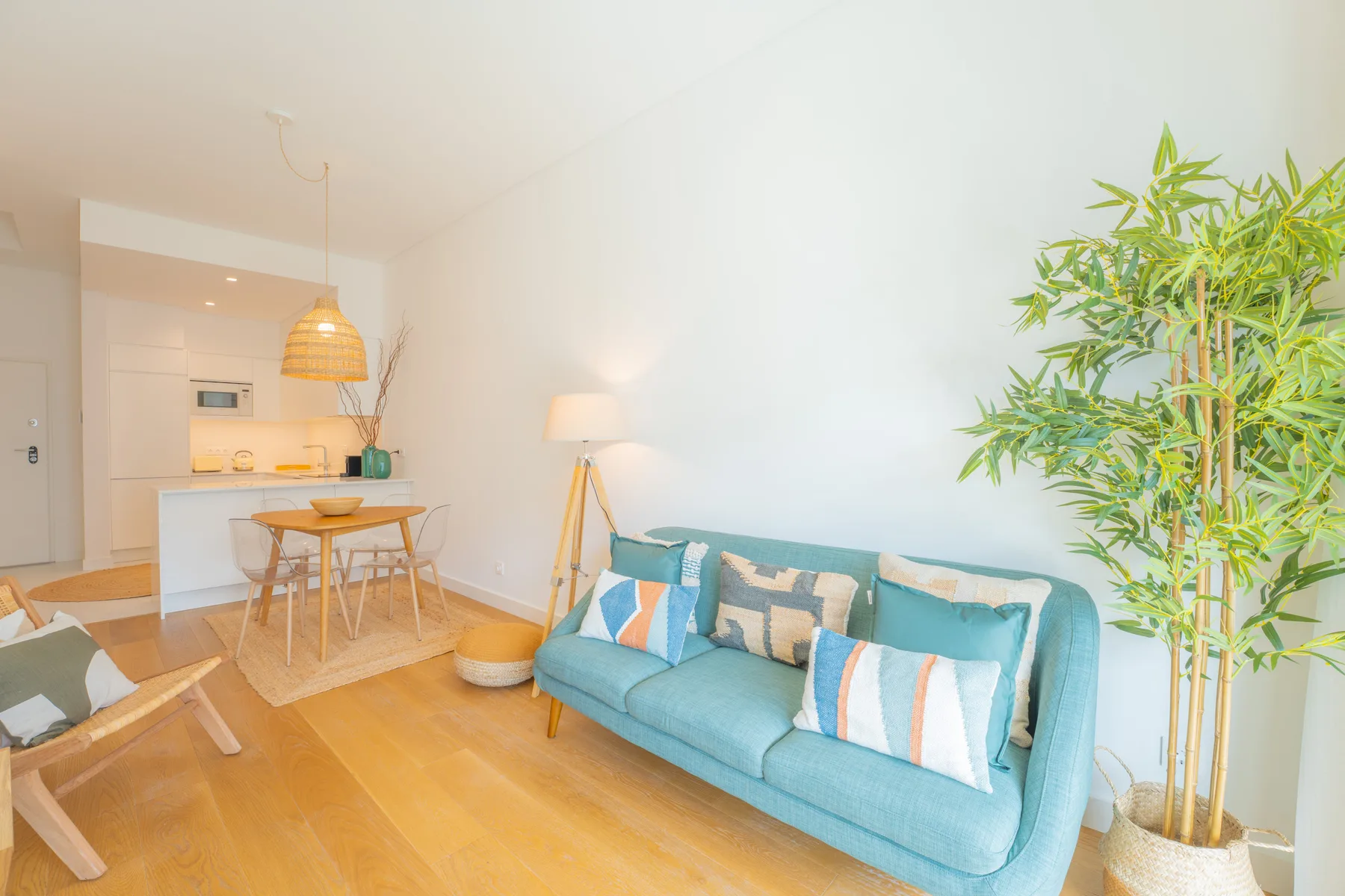 Una sala luminosa con asientos turquesa, una mesa de comedor y una planta alta.