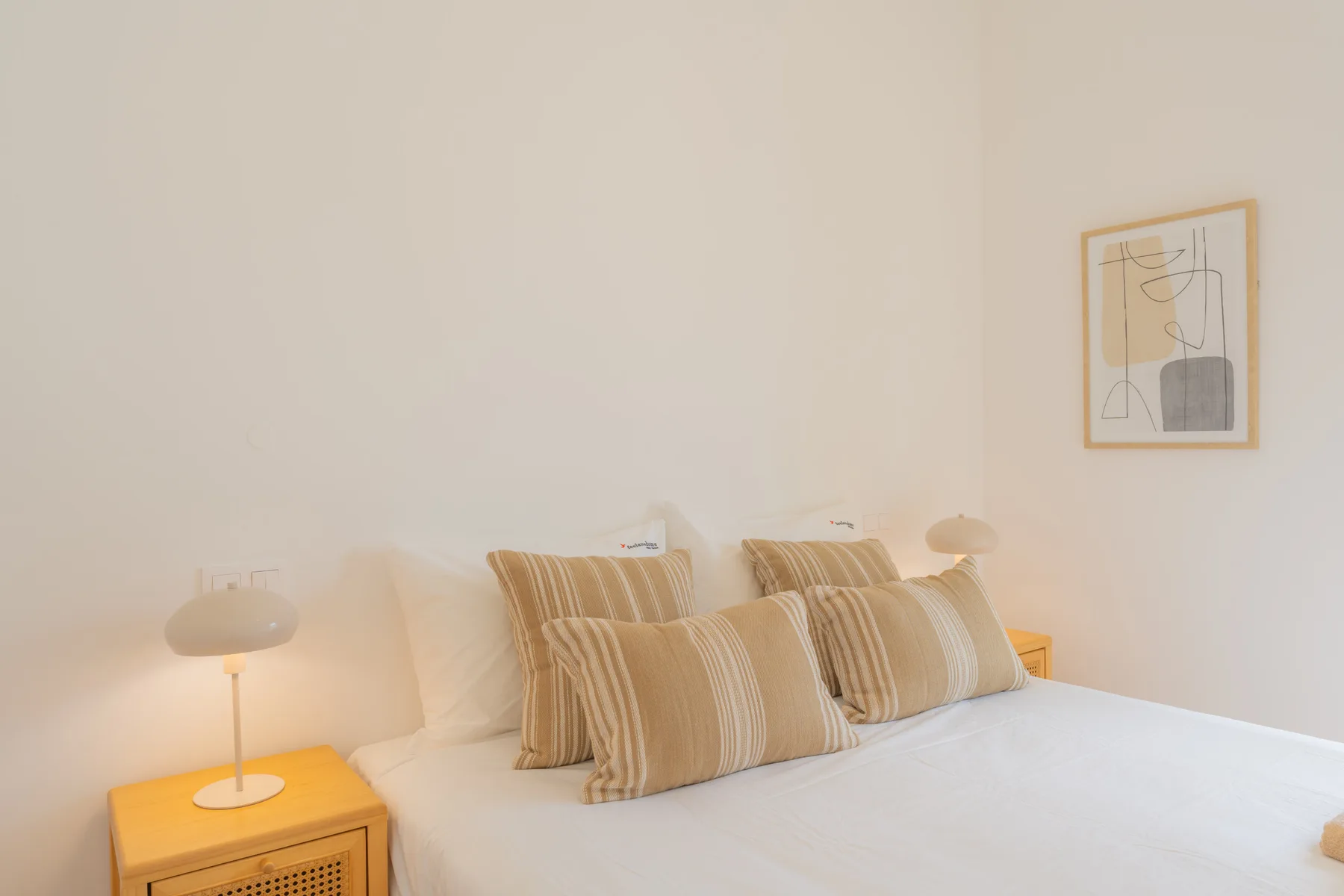 Un dormitorio con una cama bien arreglada y una obra enmarcada en la pared.