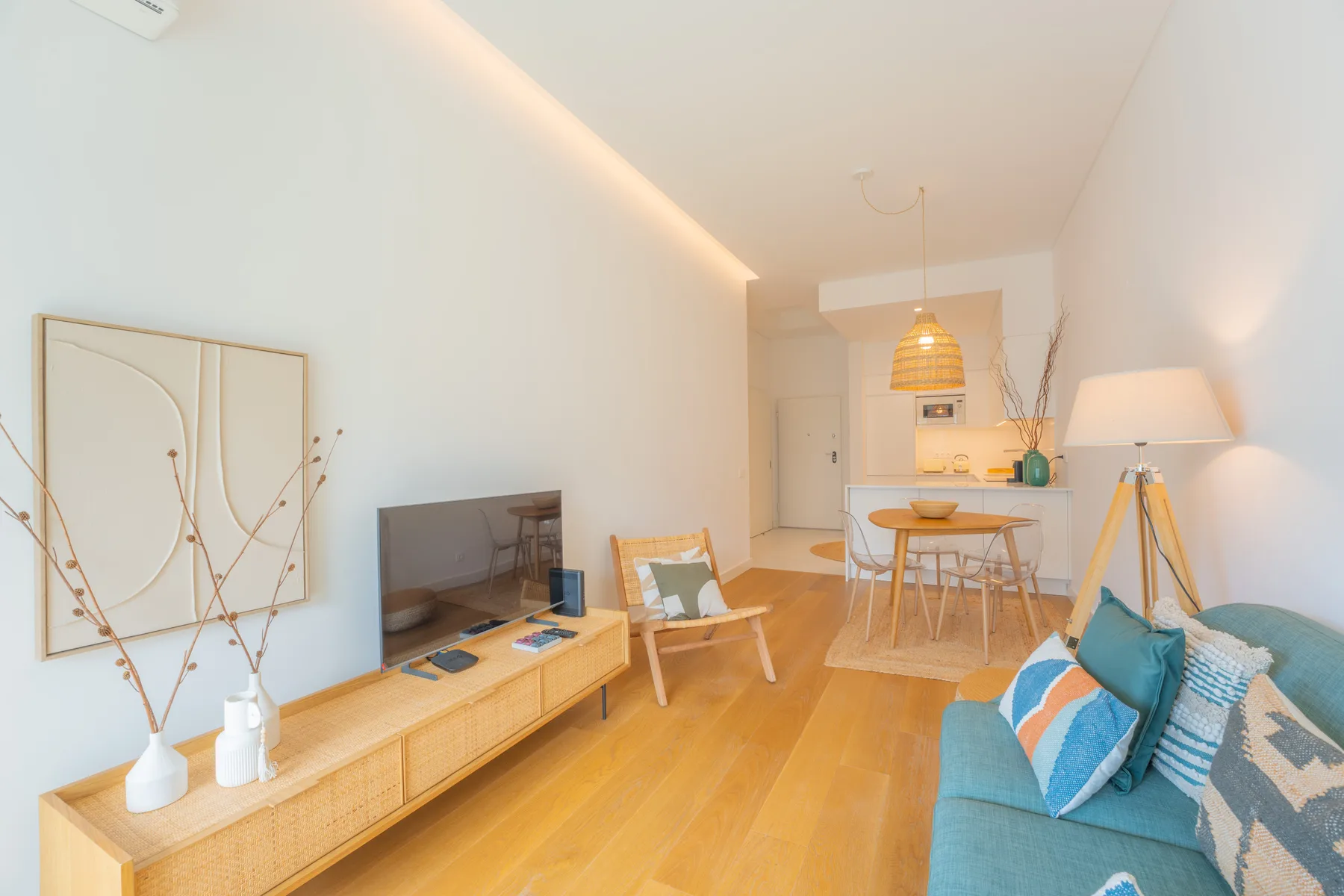 Una luminosa sala de estar y comedor con asientos, un televisor y suelo de madera.