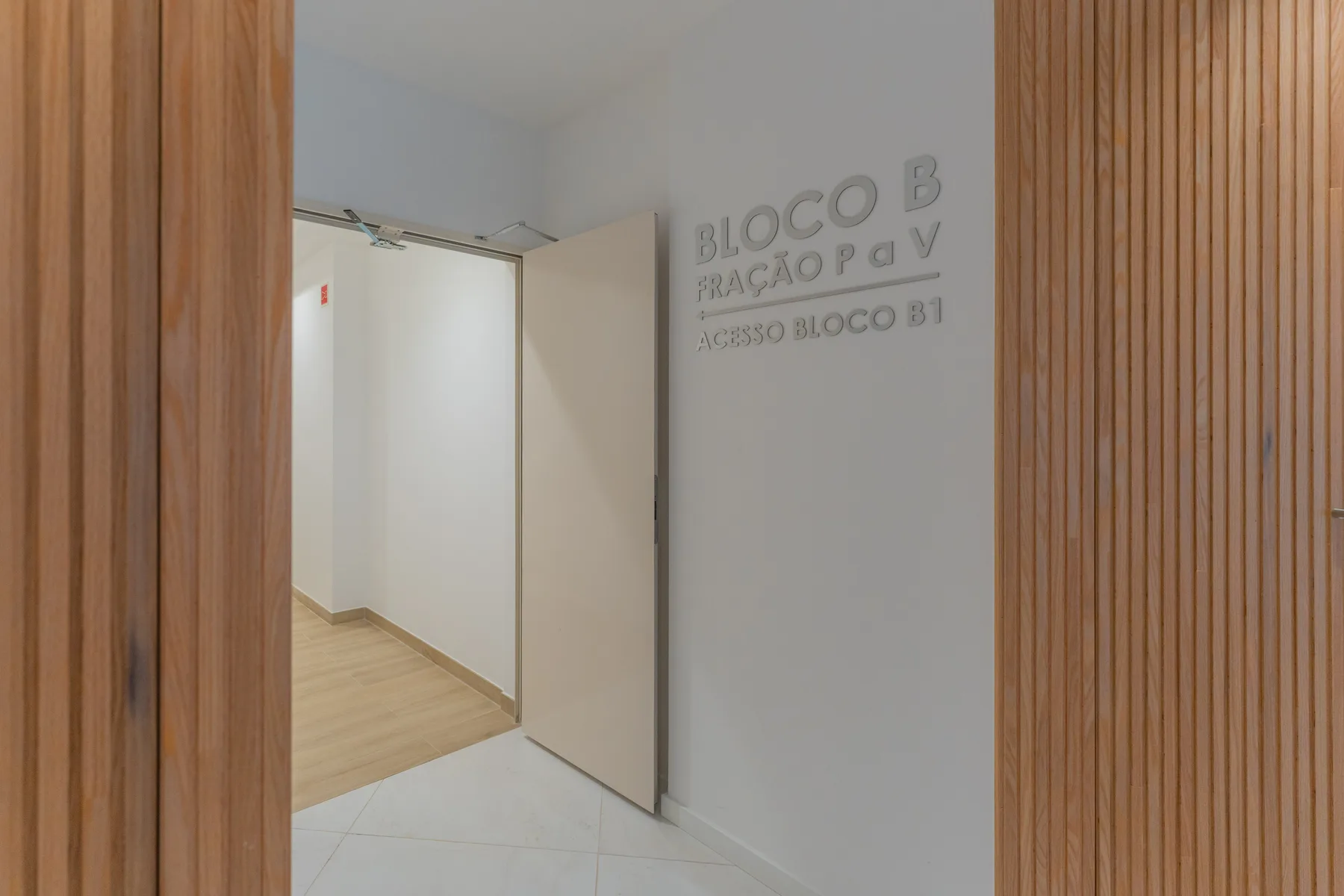 Entrada de un pasillo del edificio con una puerta abierta y paneles de listones de madera.