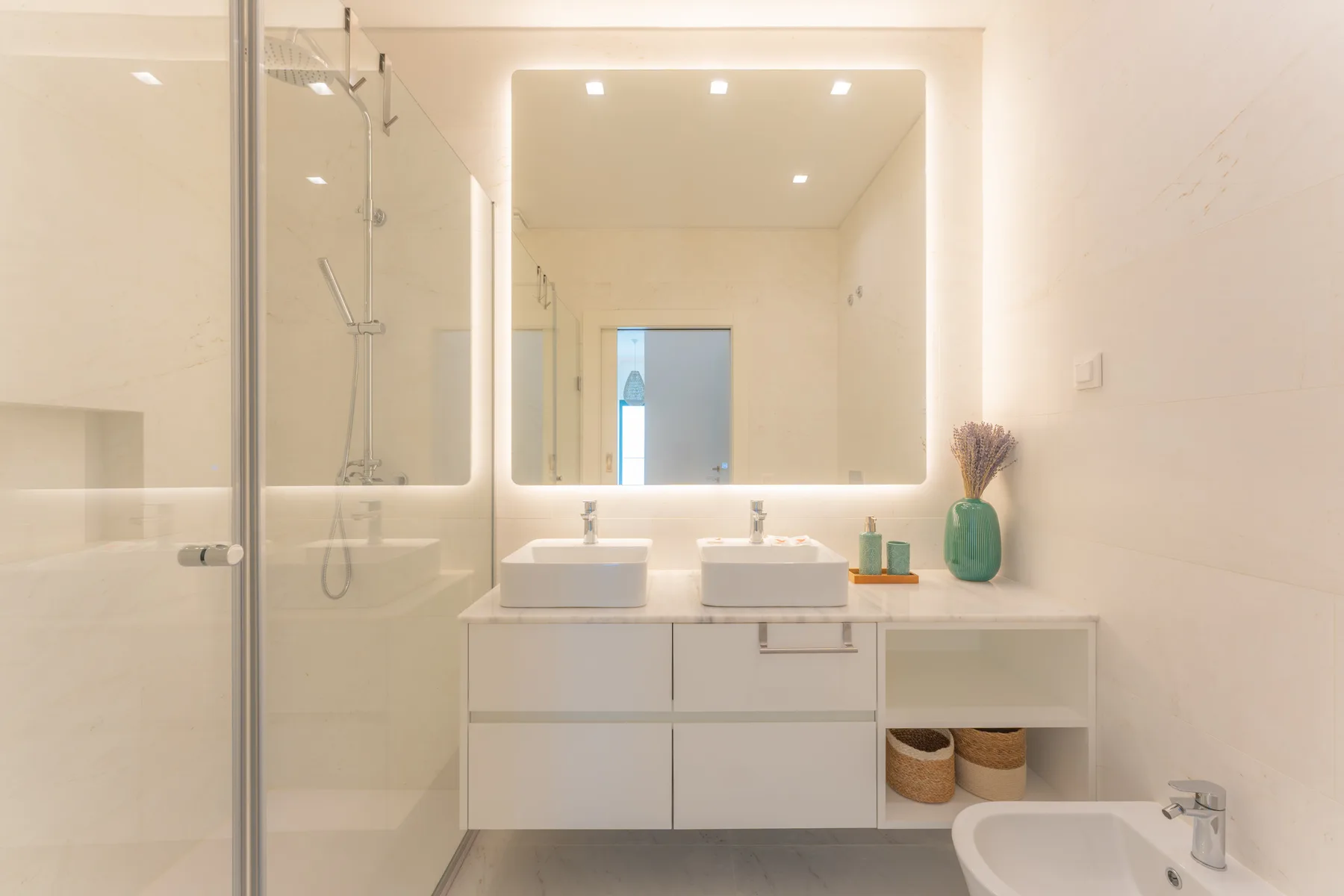 Un baño luminoso con un espejo amplio sobre un tocador con dos lavabos.