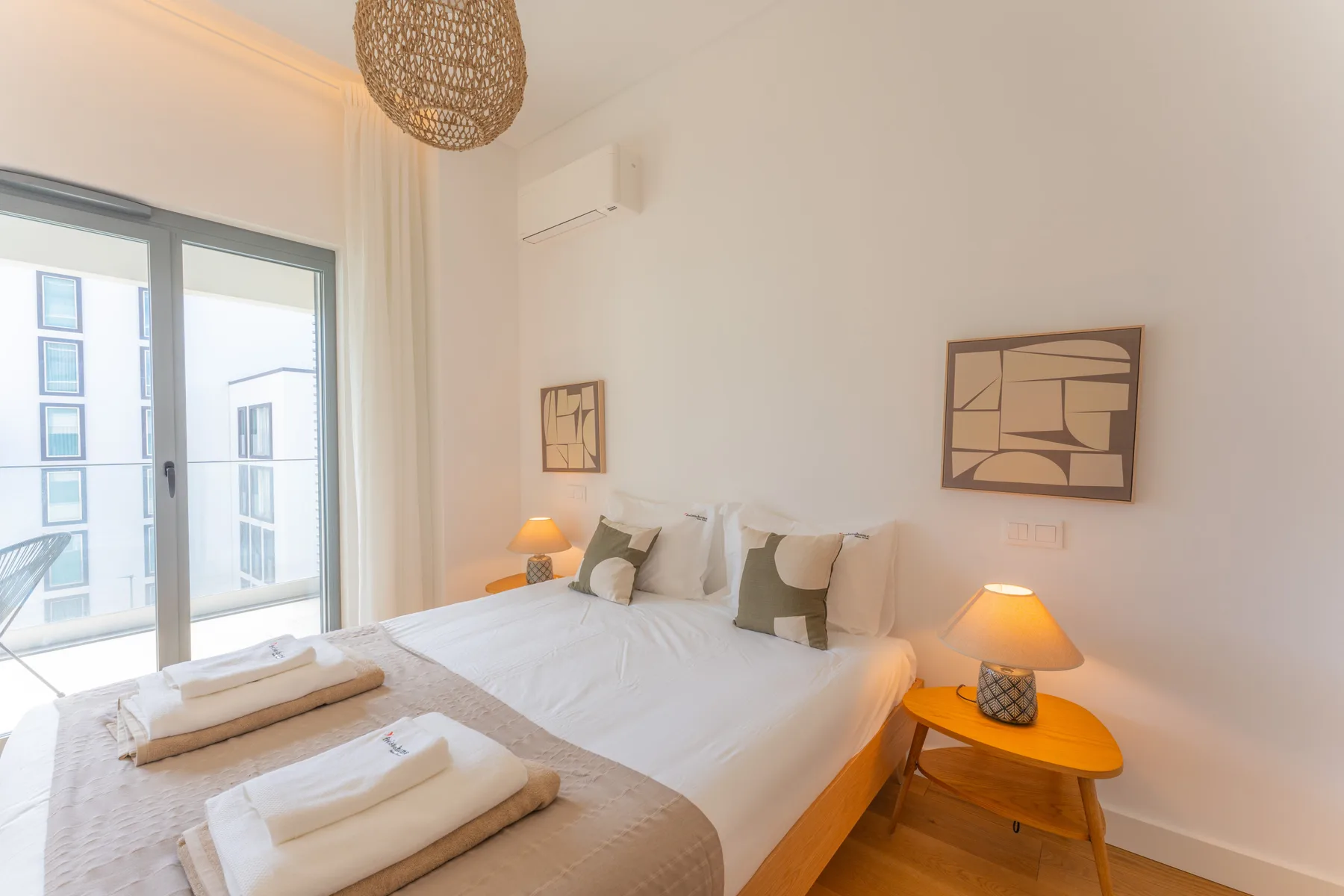 Un dormitorio luminoso con una cama grande, mesas de noche y puertas corredizas de vidrio.