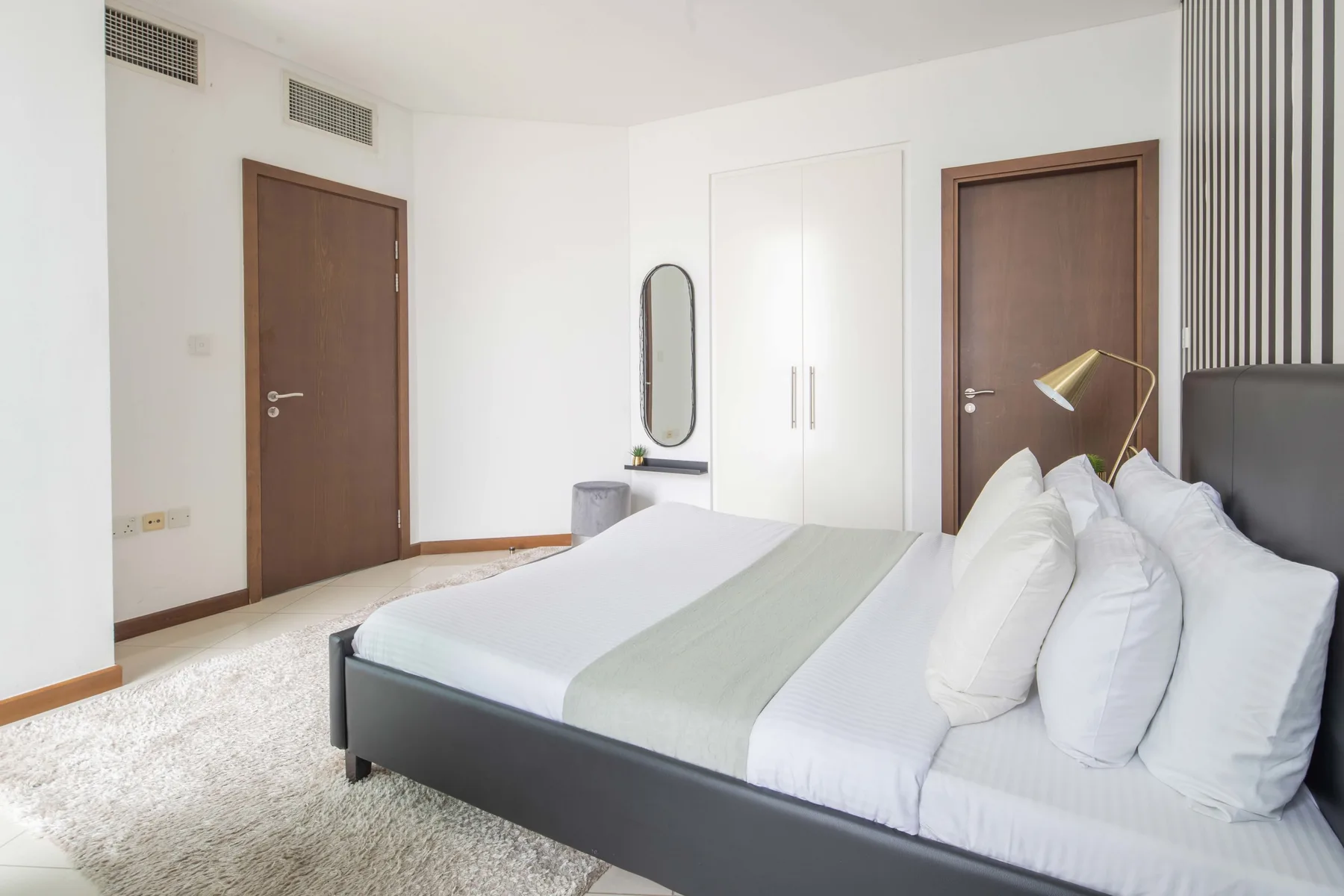 Un dormitorio luminoso con una cama tendida y un armario blanco.