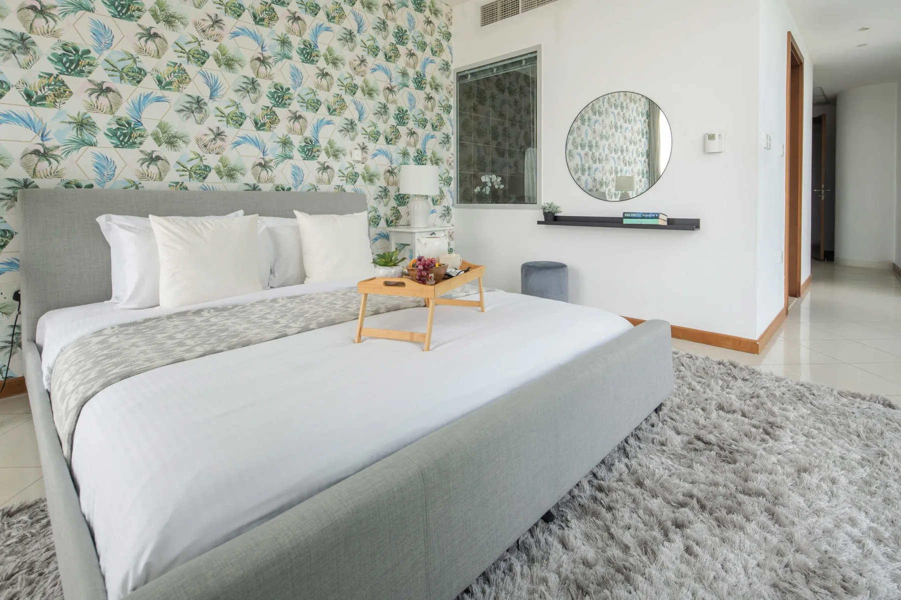 Un dormitorio luminoso con una cama bien tendida y papel tapiz botánico estampado.