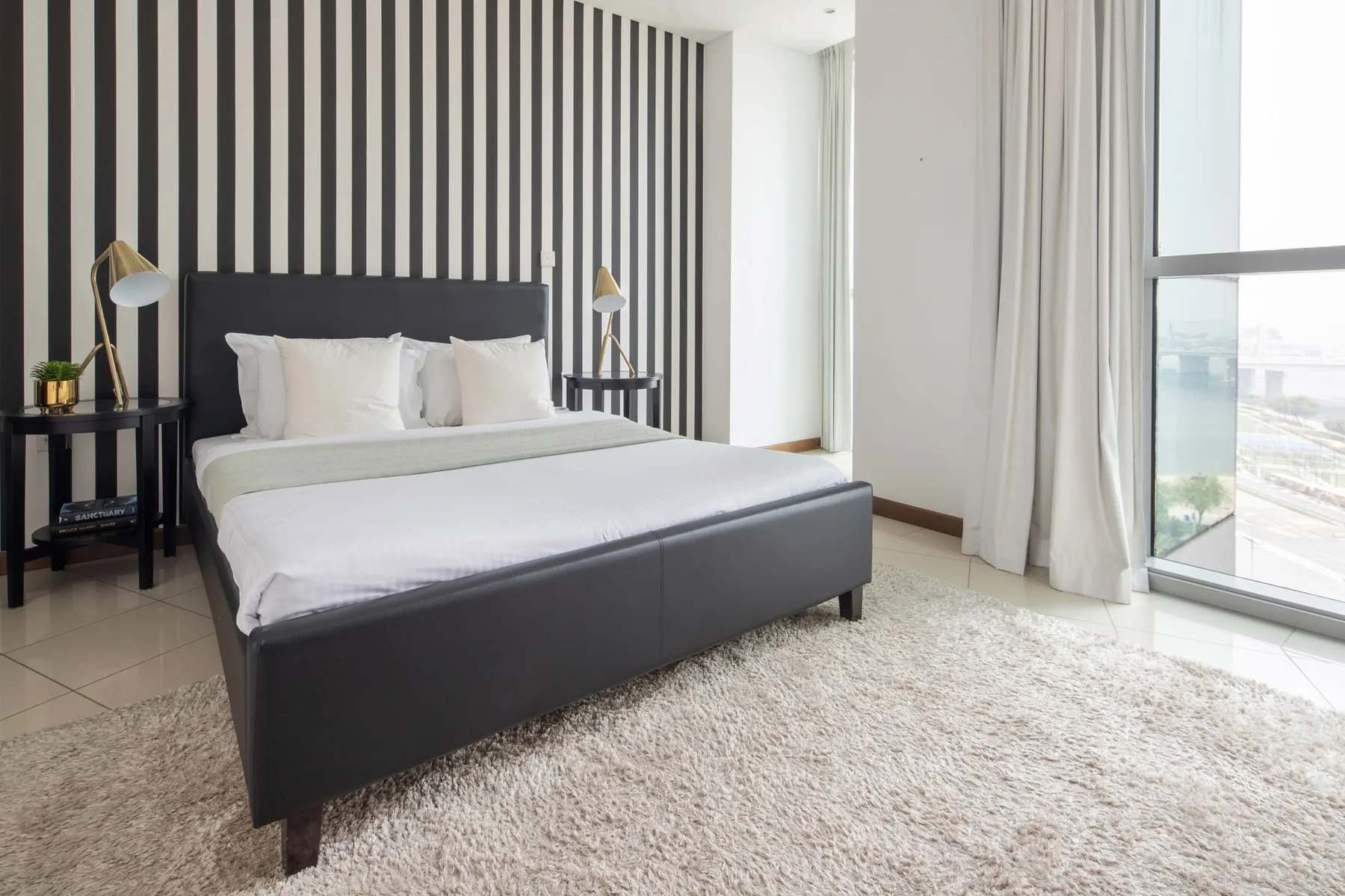 Un dormitorio luminoso con una cama grande junto a ventanales.