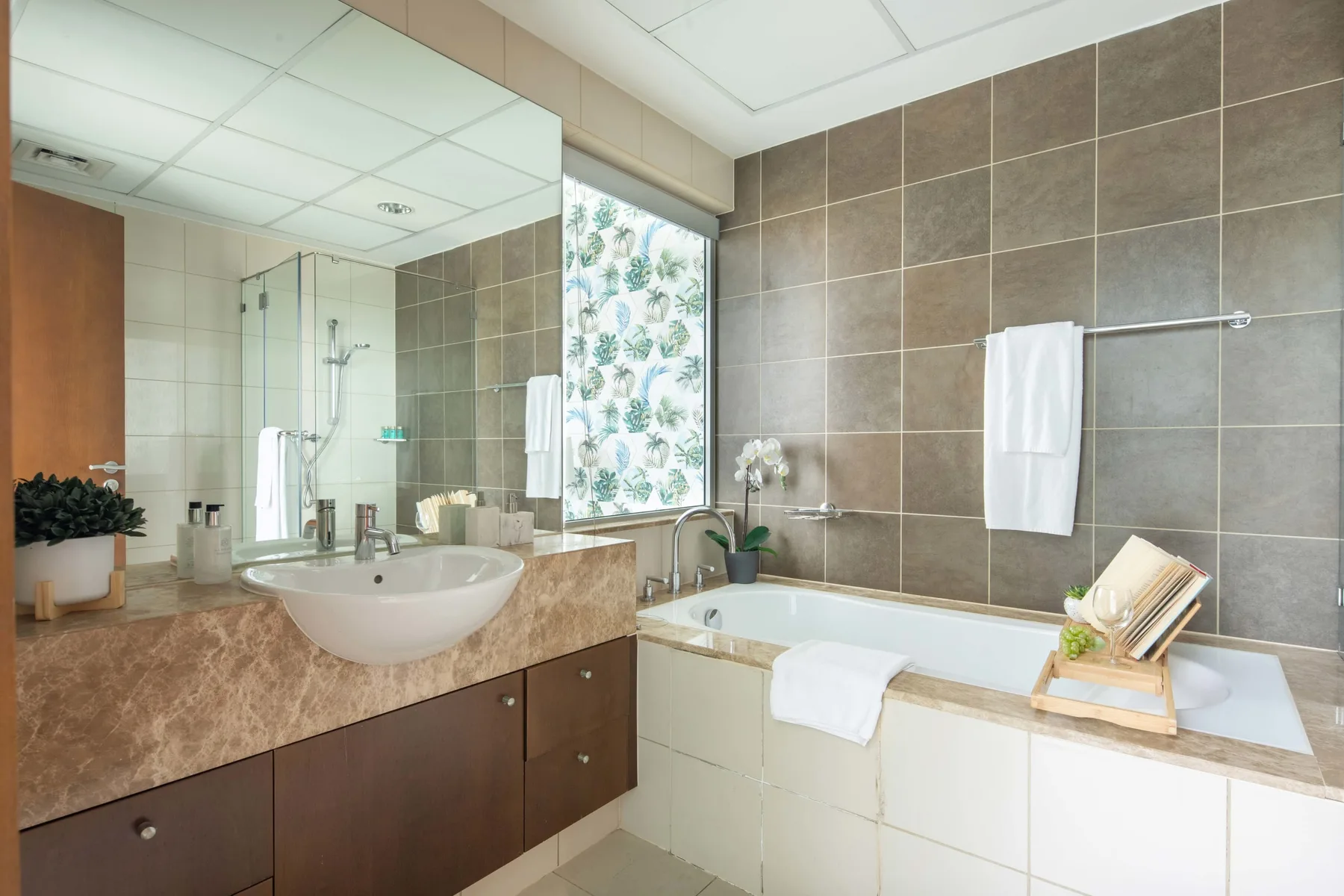 Un baño con un lavabo junto a una bañera y paredes revestidas de azulejos.