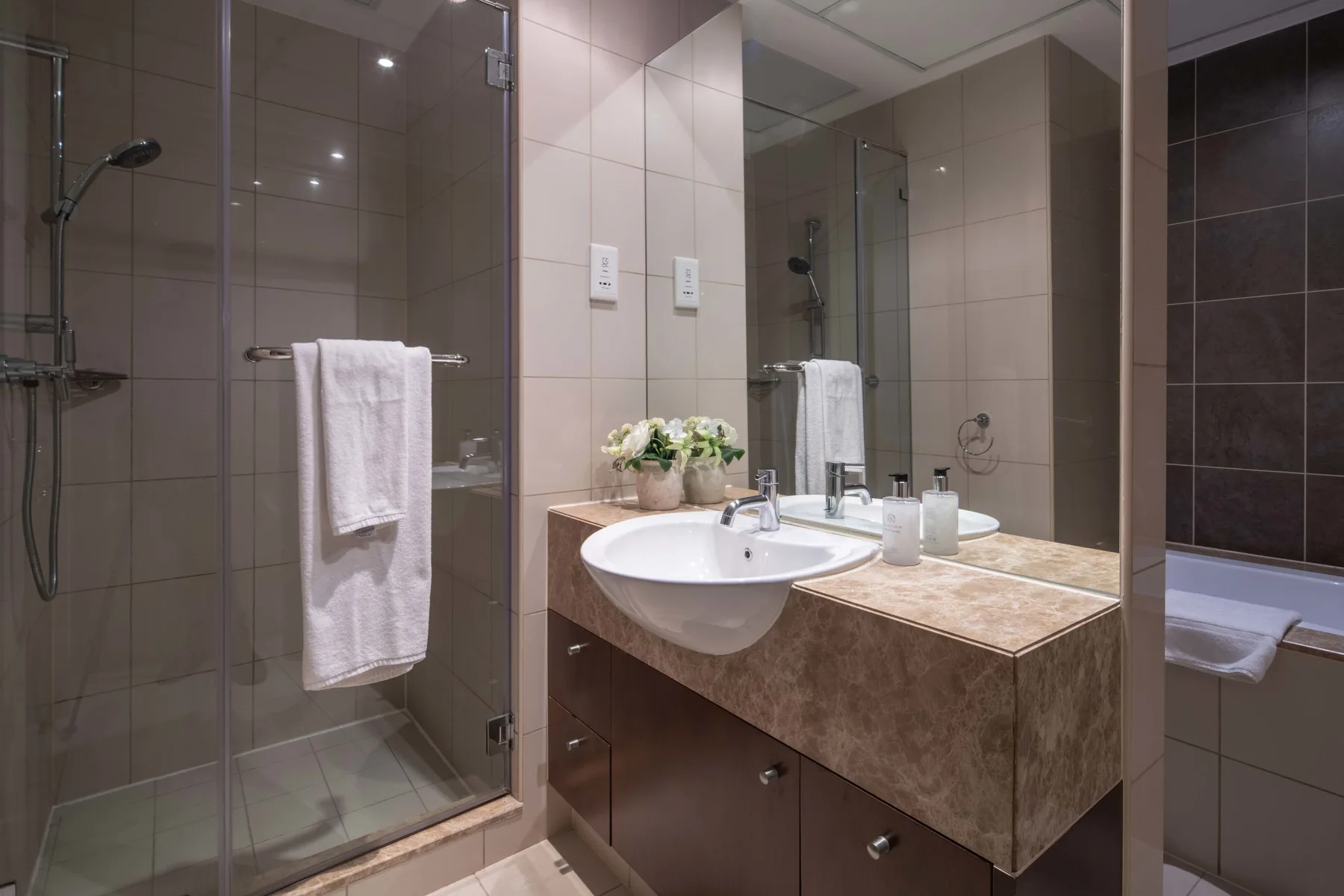 Un baño con azulejos, una ducha de vidrio y un lavabo.