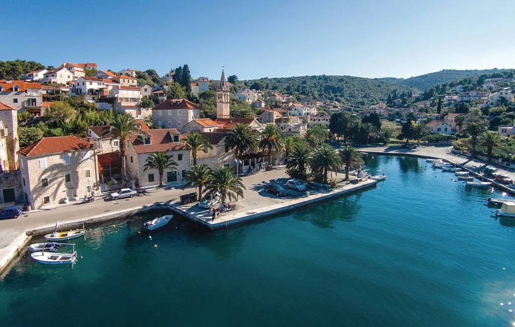 A coastal village with waterfront buildings and boats along a blue harbor.