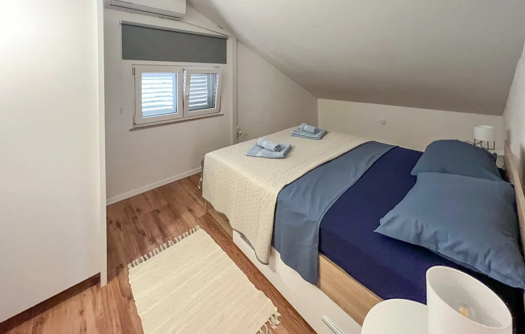 An attic bedroom with two beds and a small window.