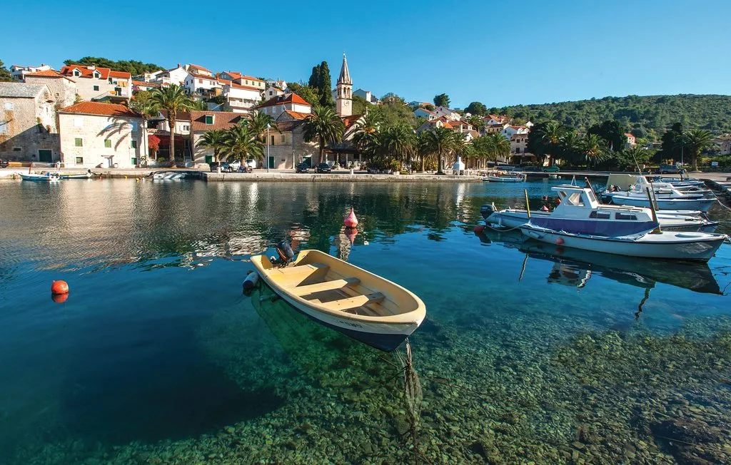 A clear harbor with small boats anchored beside a waterfront town.
