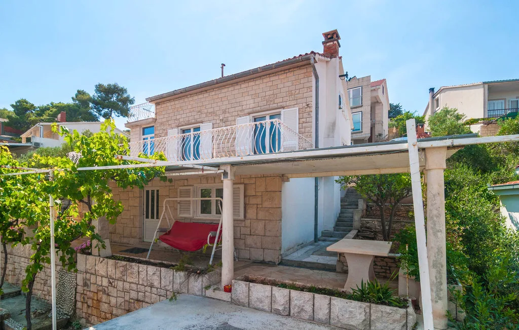 A stone house exterior with a covered patio and red seating.