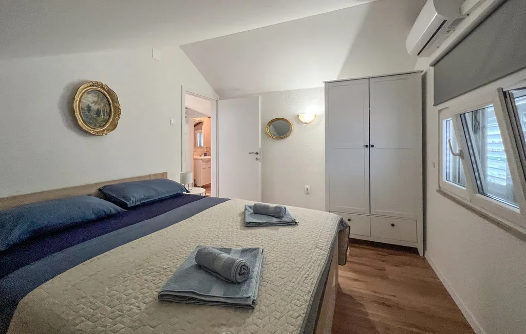 A bedroom with a made bed, wardrobe, and windows.